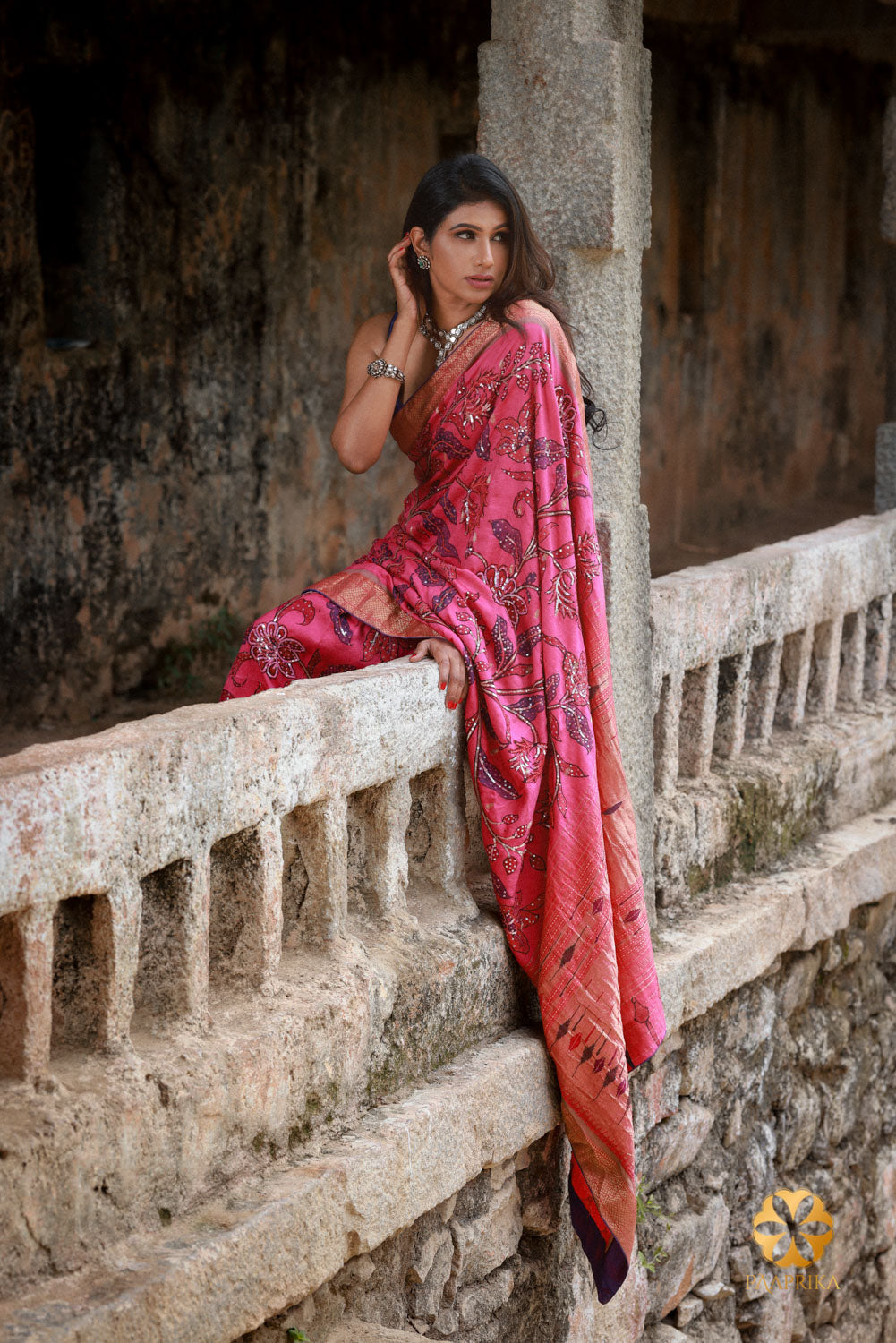 A stylish woman confidently wearing the Hot Pink Paithani Silk Saree with Kalamkari and Sequin Embroidery. The saree's vibrant color, Kalamkari motifs, and sequin embellishments enhance her overall look, radiating elegance and sophistication.