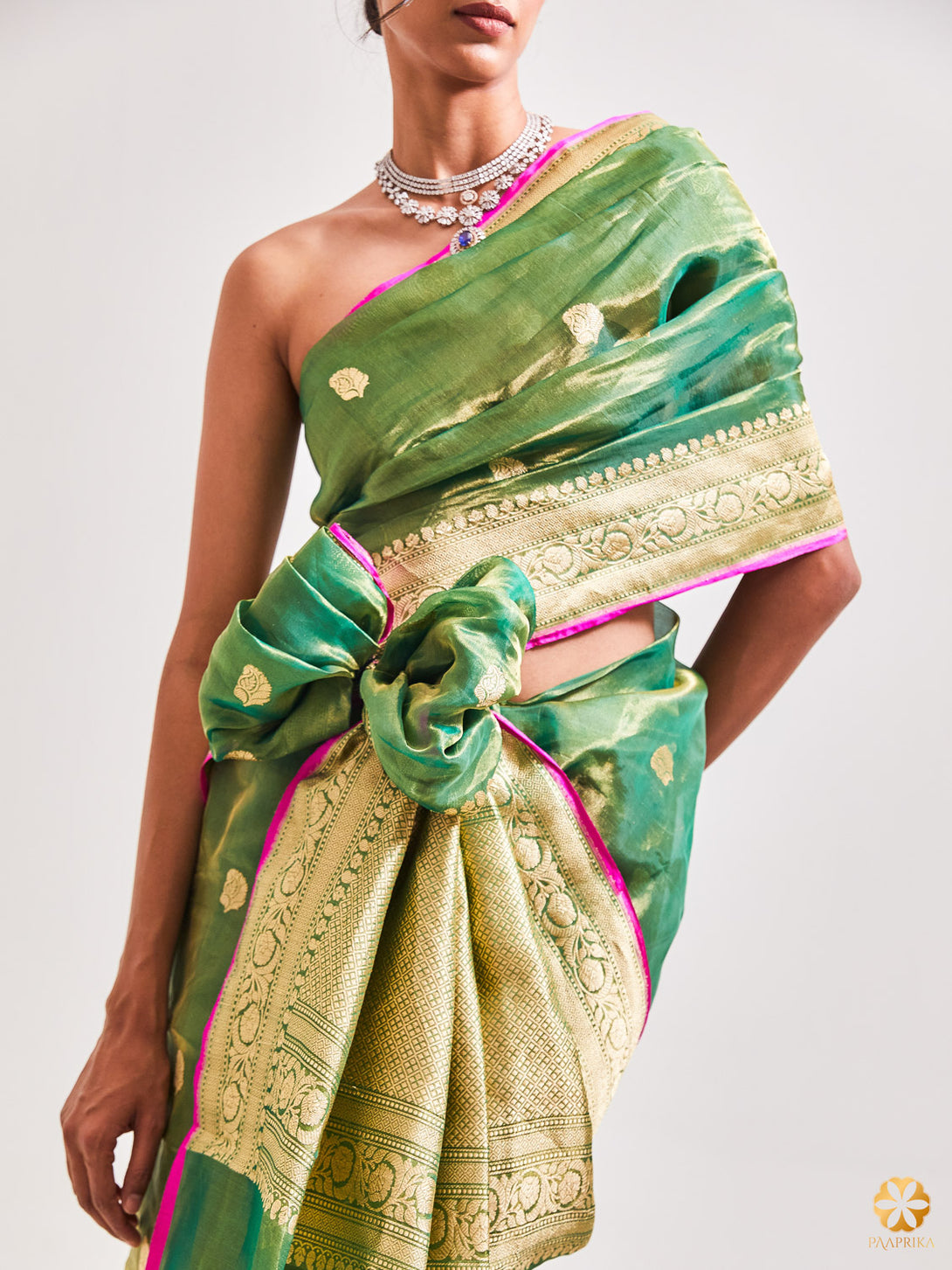 A Stylish Woman Wearing Exquisite Bottle Green and Gold Handwoven Tissue Saree - Effortless Elegance and Vibrancy.