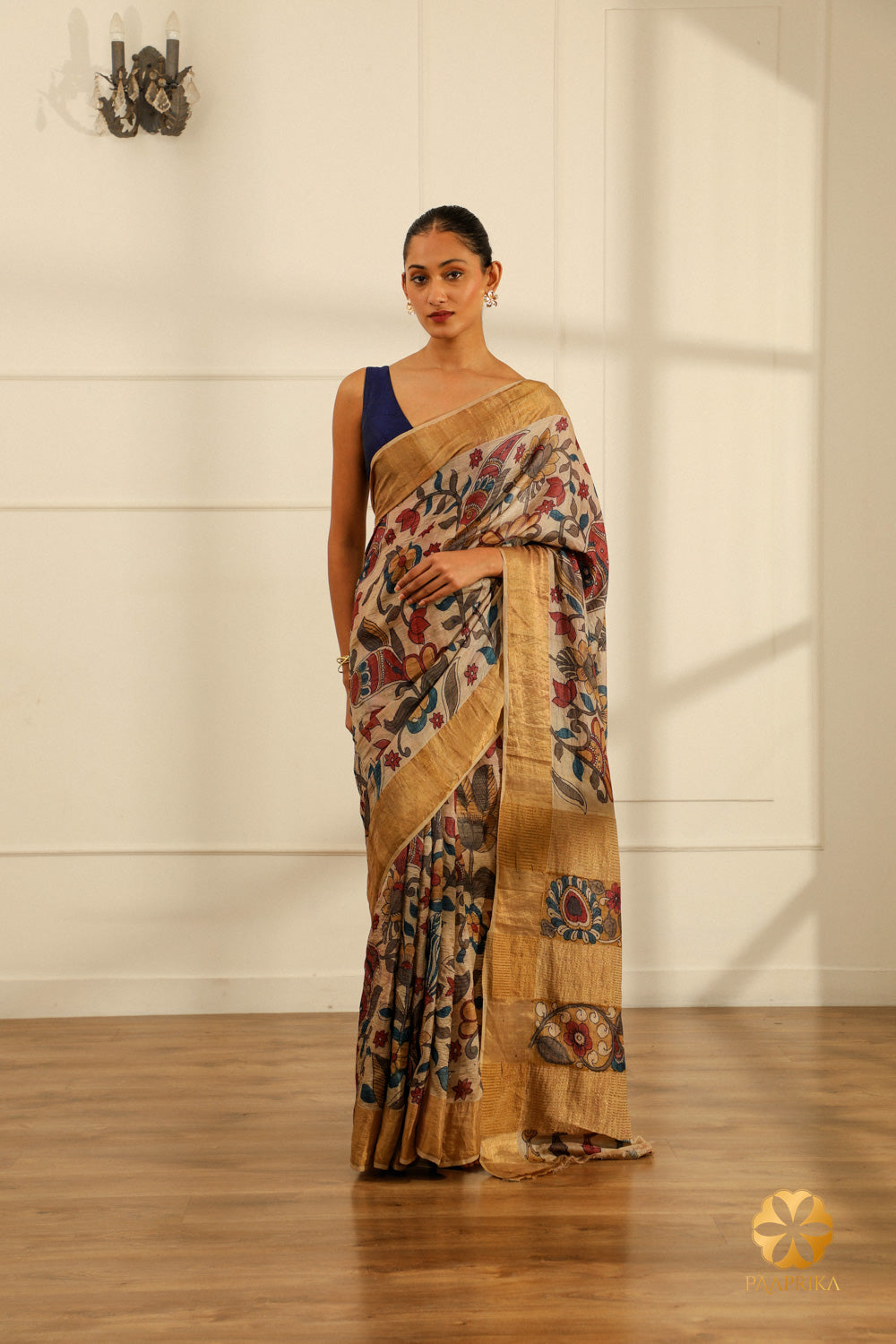 A full-length shot of a woman gracefully draped in the Cream Tussar Silk Saree, showcasing its elegance and the artistic floral creepers and leaves motifs.
