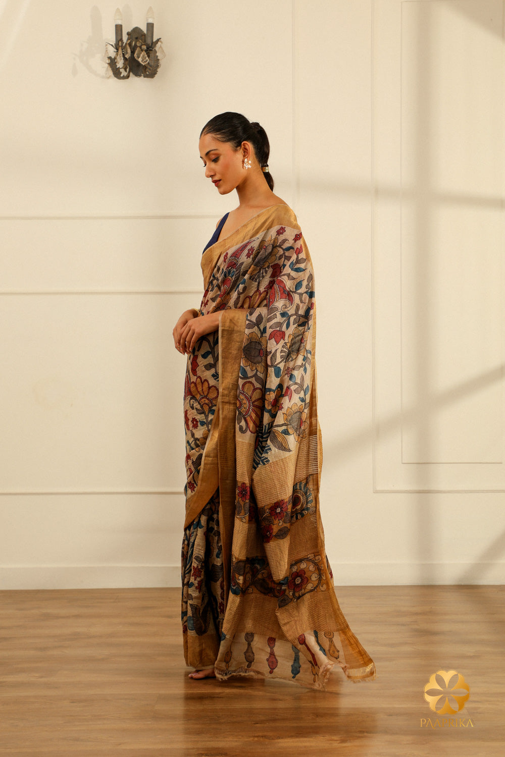 A close-up of the saree's pallu, highlighting the intricate floral creepers and leaves motifs and their naturalistic detailing against the cream background.