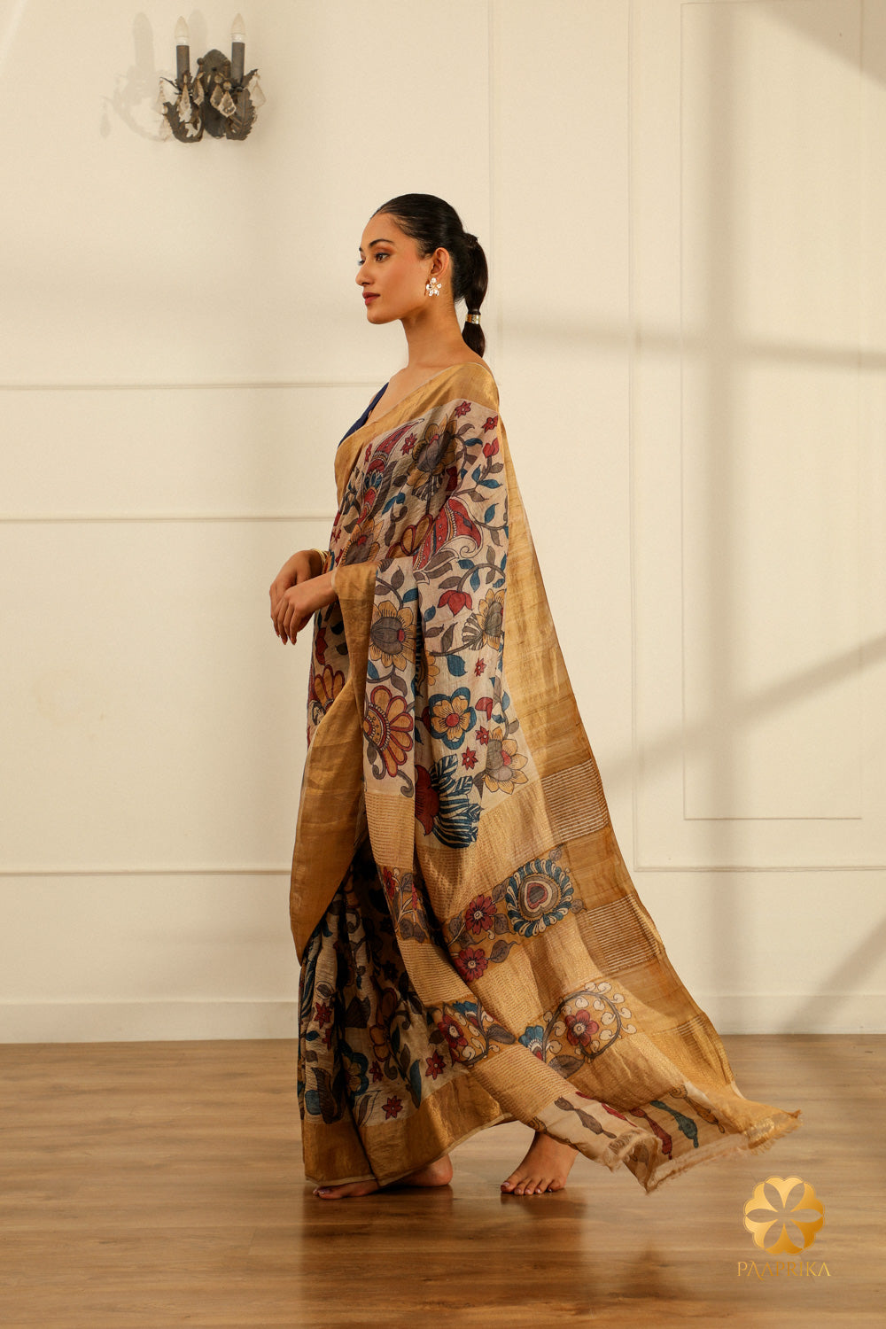 The saree elegantly displayed on a mannequin, capturing the beauty of the Kalamkari floral motifs and the lustrous Tussar silk in a serene cream hue.