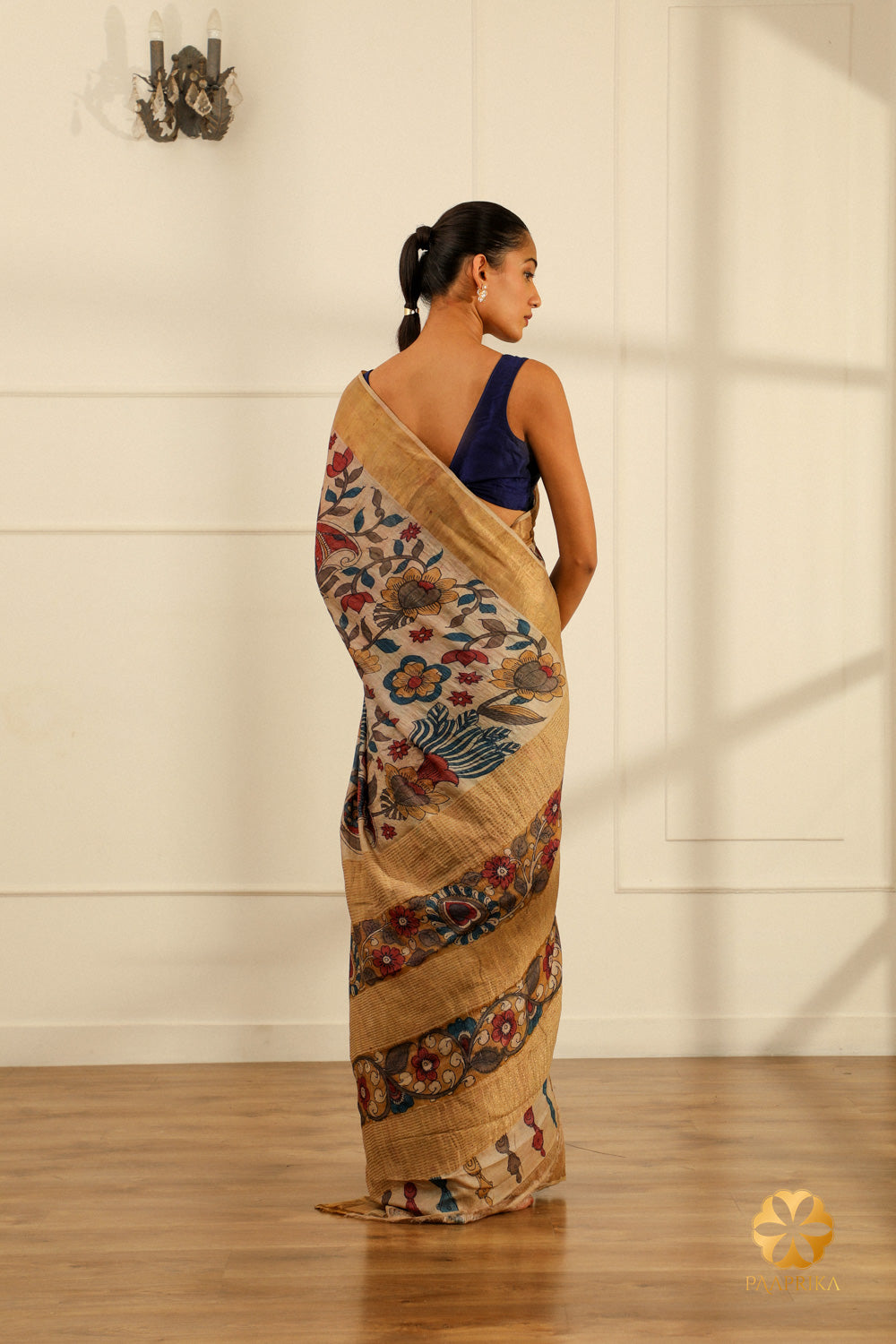 The saree elegantly displayed on a mannequin, capturing the beauty of the Kalamkari floral motifs and the lustrous Tussar silk in a serene cream hue.