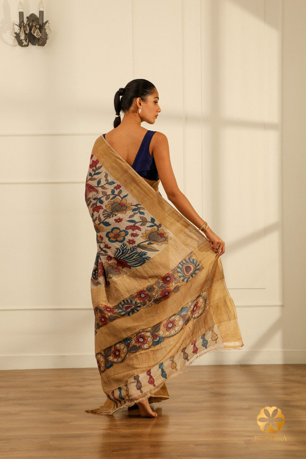 A full-length shot of a woman gracefully draped in the Cream Tussar Silk Saree, showcasing its elegance and the artistic floral creepers and leaves motifs.