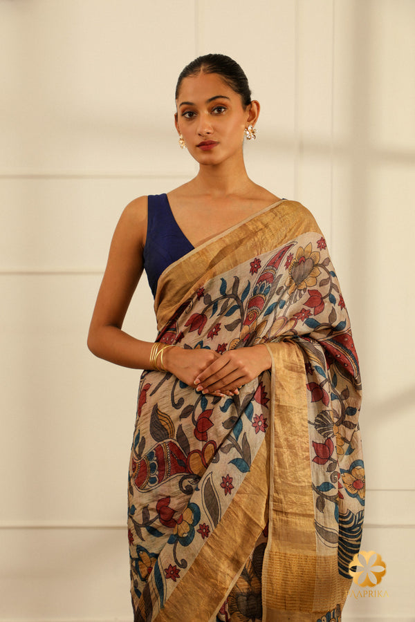The saree elegantly displayed capturing the beauty of the Kalamkari floral motifs and the lustrous Tussar silk in a serene cream hue.