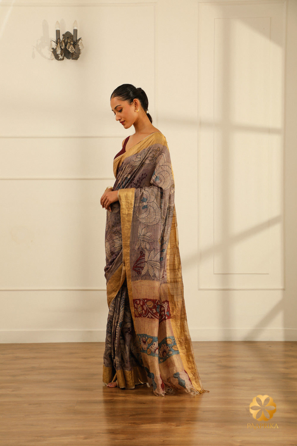 A full-length shot of a woman gracefully draped in the Tussar Grey Silk Saree, showcasing its elegance and the artistic palm tree motifs.
