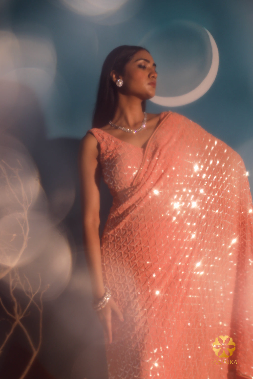 Dazzling peach sequins saree showcasing an exquisite geometric embroidery pattern. Make a statement at cocktail parties. Customization available. Visit our website for details.