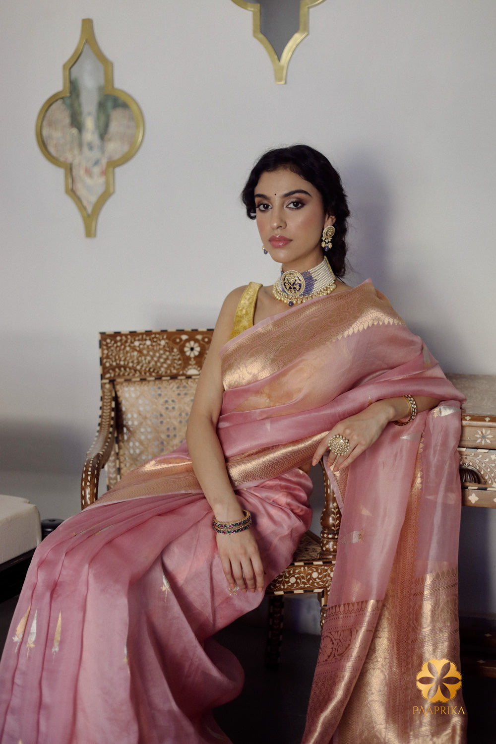 Pastel Onion Pink Banarasi Organza Saree paired with complementary accessories. The saree's delicate pastel hue and intricate handwoven pattern create a stunning ensemble, harmoniously complemented by the accessories for a complete and elegant appearance.