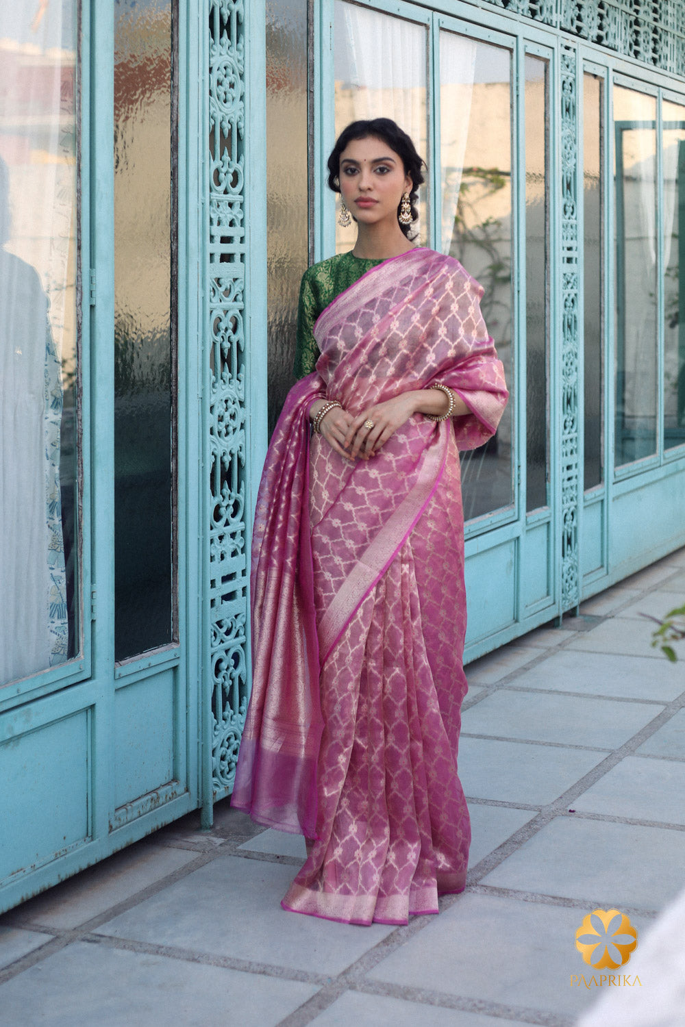 A close-up view of a handwoven pink and gold tissue saree showcasing intricate golden motifs and delicate rose petal-like shade of pink.
