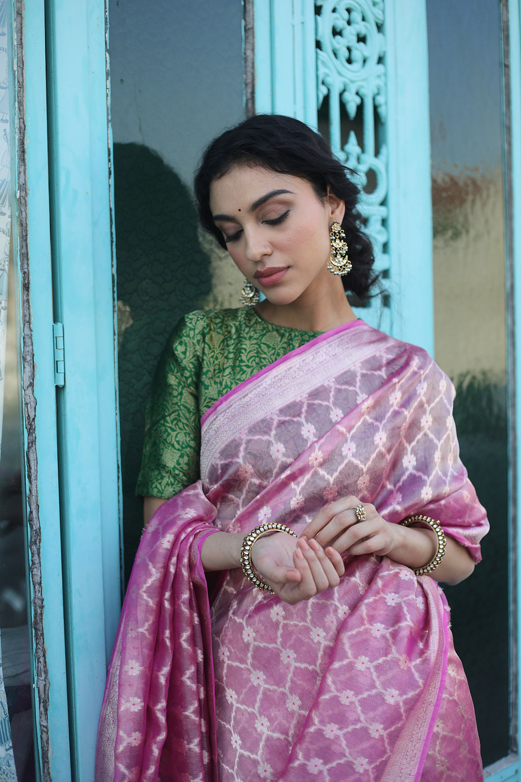 A woman wearing the pink and gold tissue saree at a wedding, radiating elegance and sophistication, making it an ideal choice for weddings and special events.