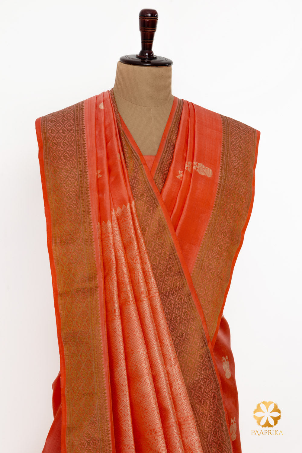 Detailed craftsmanship of Ganda Berunda motifs on a coral silk saree.