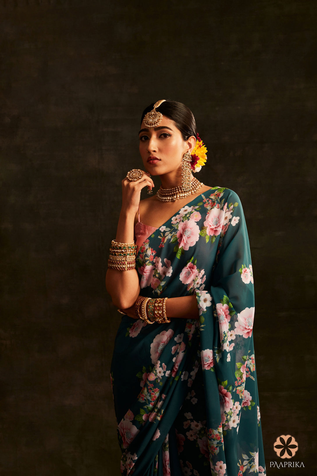 A stylish woman confidently wearing the Exquisite Teal Green Floral Printed Georgette Saree, embodying grace and elegance with the saree's serene floral blooms. The saree's floral prints enhance her overall look, radiating sophistication and charm.