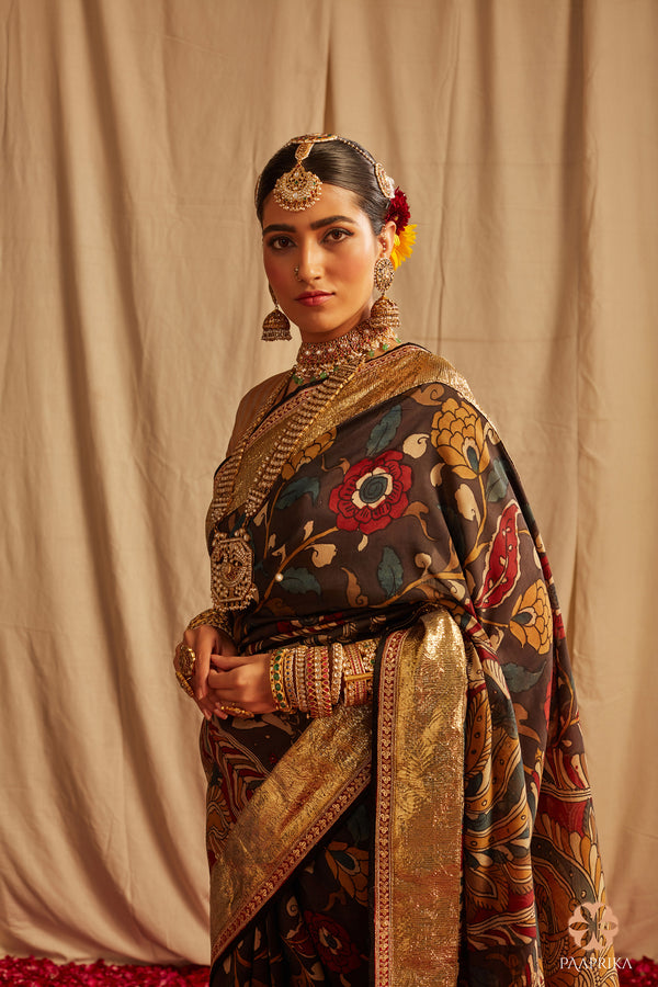 Black Authentic Kalamkari Saree with Mirror & Gotapatti Details. The saree features a black base with vibrant handcrafted Kalamkari designs in red, green, and yellow. Intricate mirror work and delicate gotapatti detailing add a touch of elegance and glamour